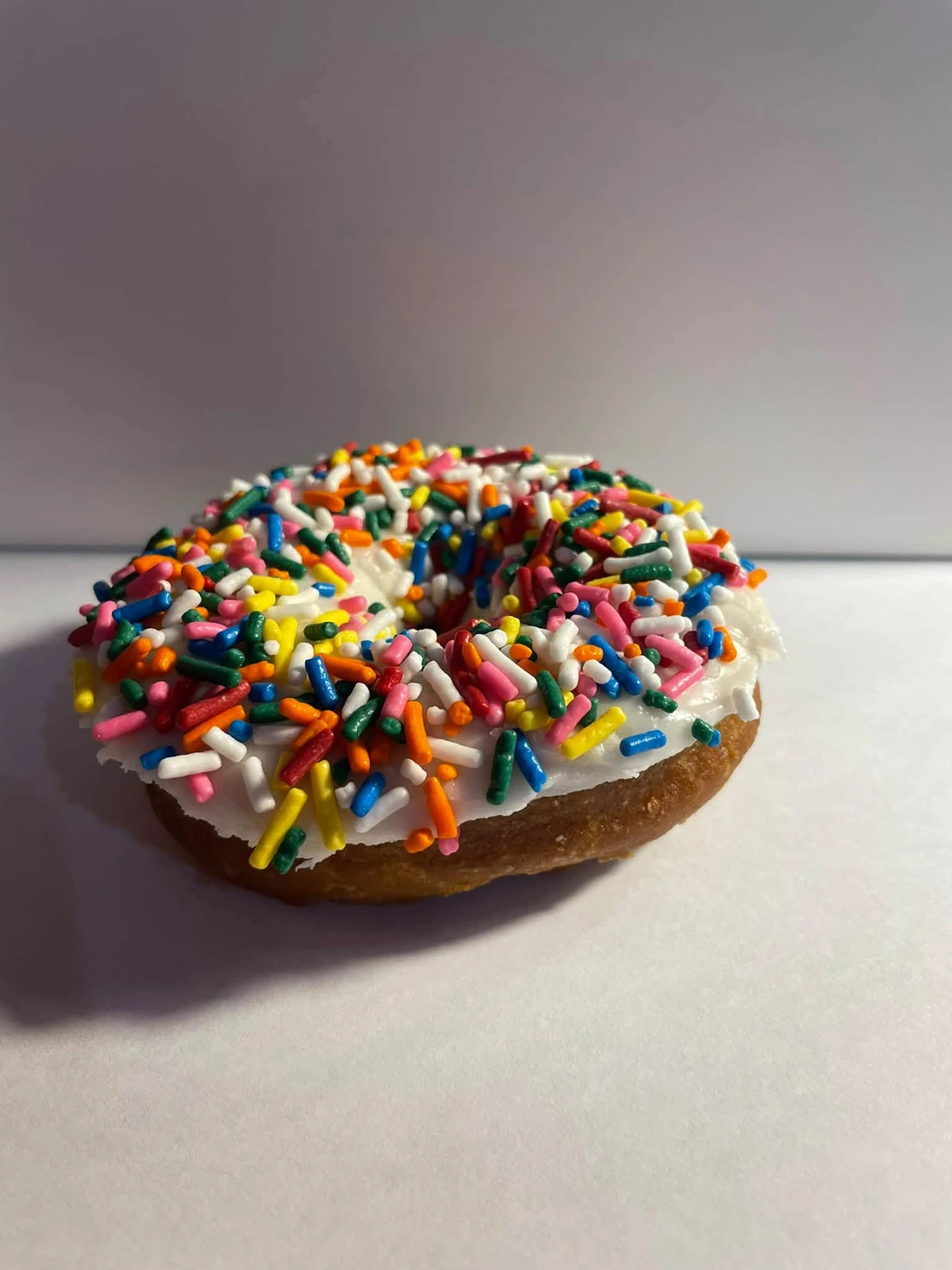 Vanilla cake donut with vanilla icing and rainbow sprinkles